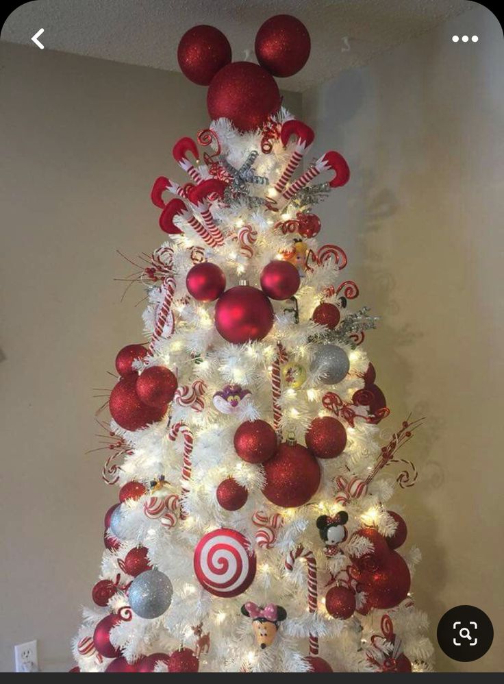 a white christmas tree decorated with red and silver ornaments, candy canes and balls