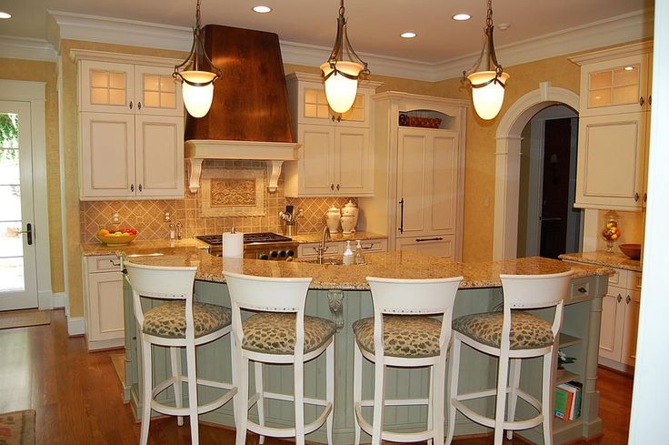 a kitchen with four stools at the center of the island and three lights hanging from the ceiling