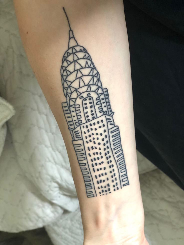 a woman's arm with a tattoo that has a building on the side of it