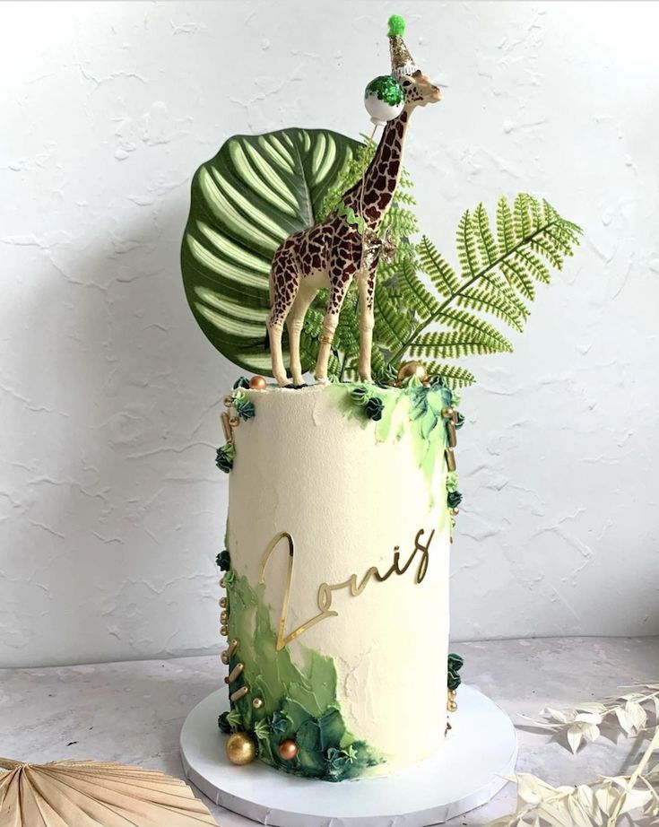 a giraffe on top of a cake surrounded by greenery