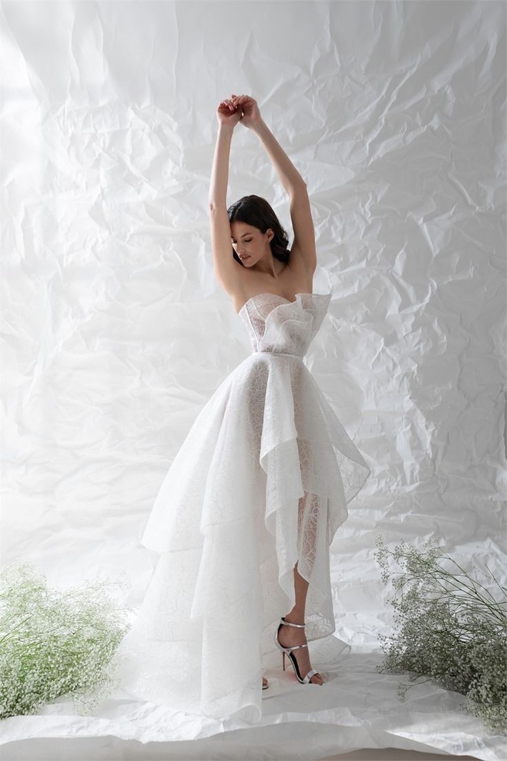 a woman in a white dress is posing for the camera with her arms above her head