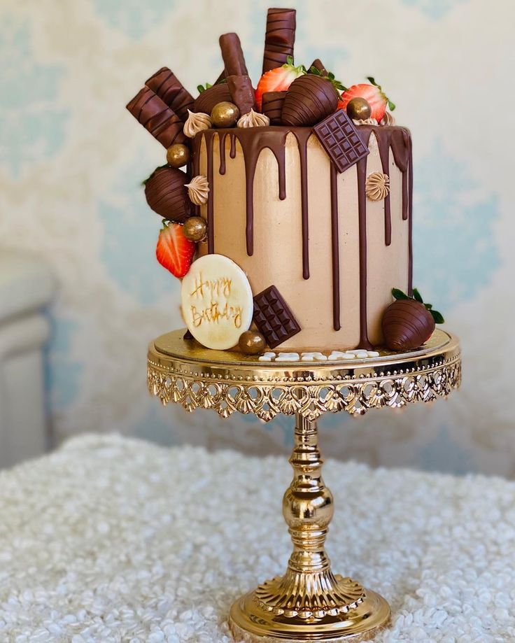 a chocolate covered cake sitting on top of a gold plate topped with strawberries and chocolate