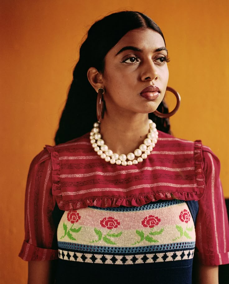 a woman in a red and white top is looking at the camera while wearing large hoop earrings