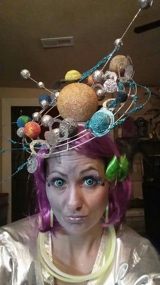 a woman wearing a space themed hat with planets on it's head and eyes