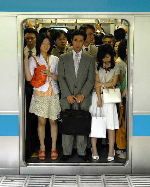 a group of people standing on a subway train with the doors open and one person holding a briefcase