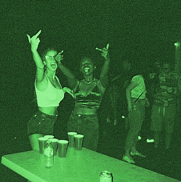 two women standing on a table with their arms in the air and one woman holding her hands up