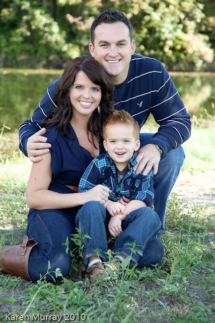 a man, woman and child are sitting in the grass with their arms around each other