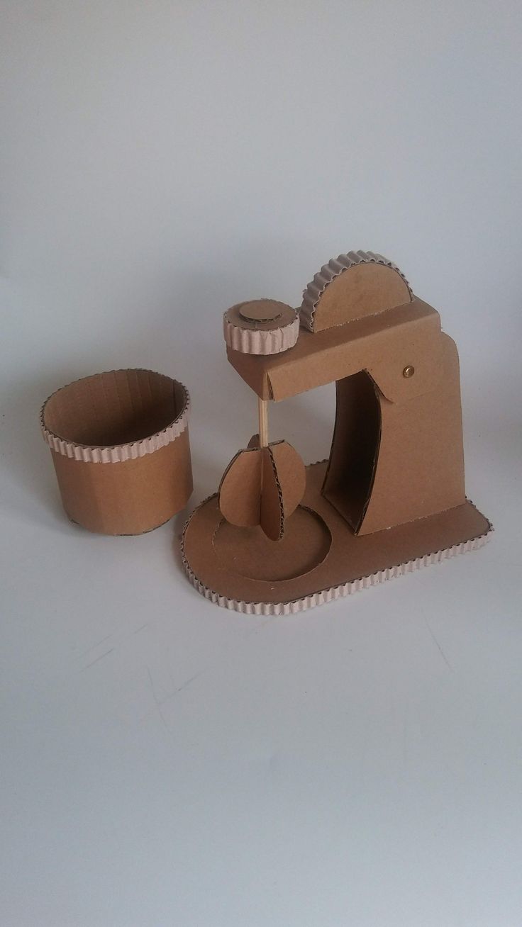 a cardboard model of an old fashioned hand held sewing machine with two cups on the side