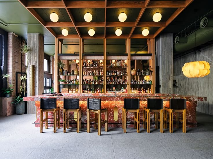 an empty bar with stools and bottles on the shelves