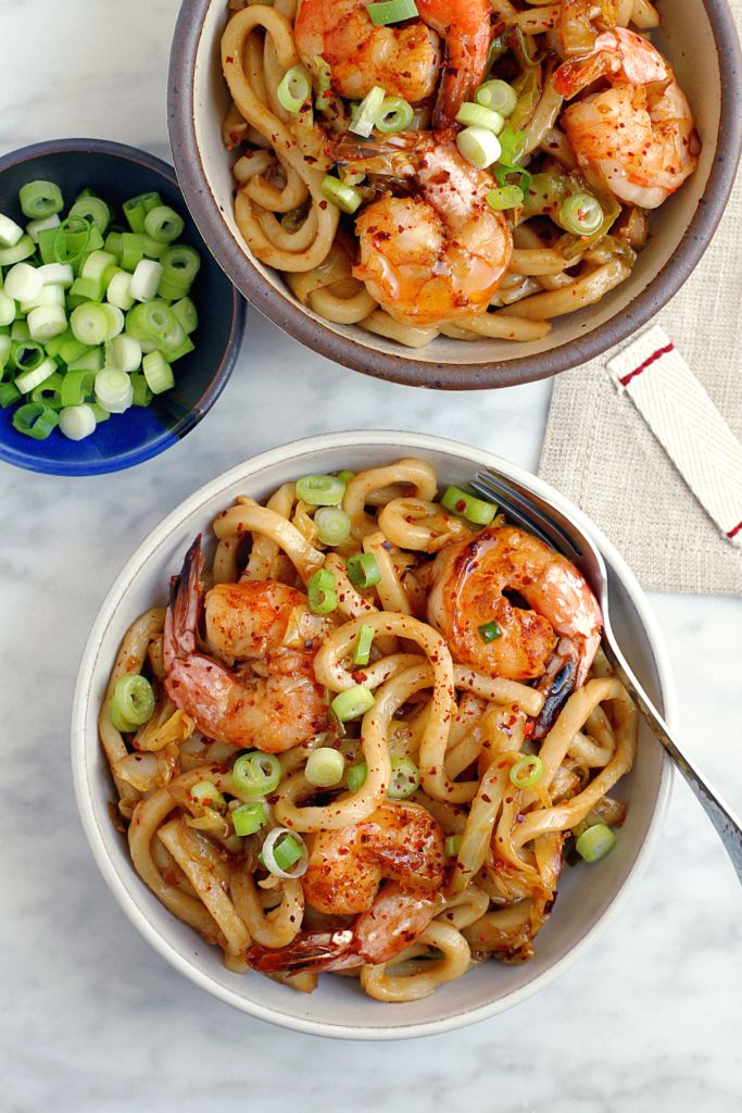 two bowls filled with shrimp, noodles and peas