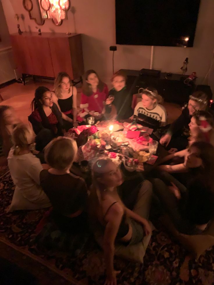 a group of people sitting around a table with a cake on it and candles in the middle