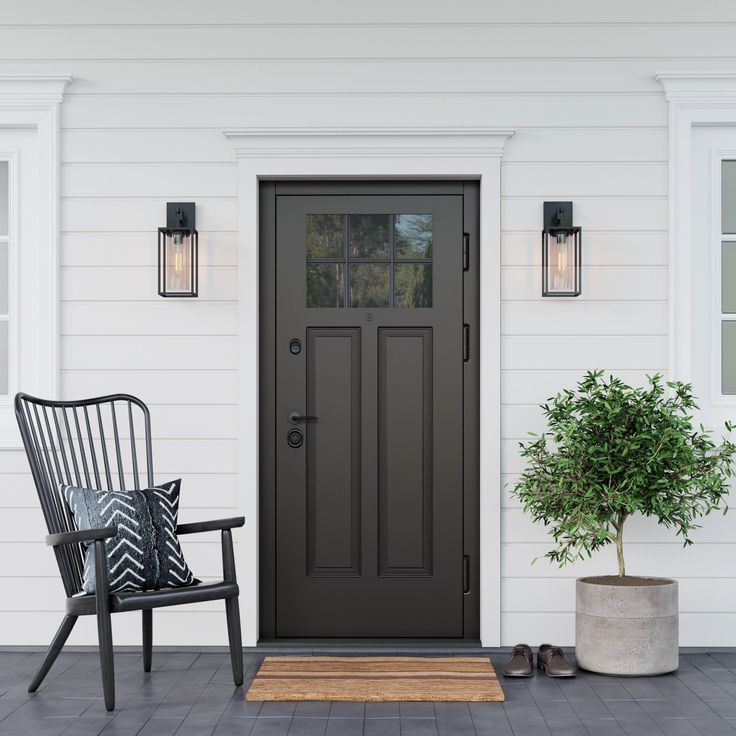 a black chair sitting in front of a door on top of a wooden floor next to a potted plant