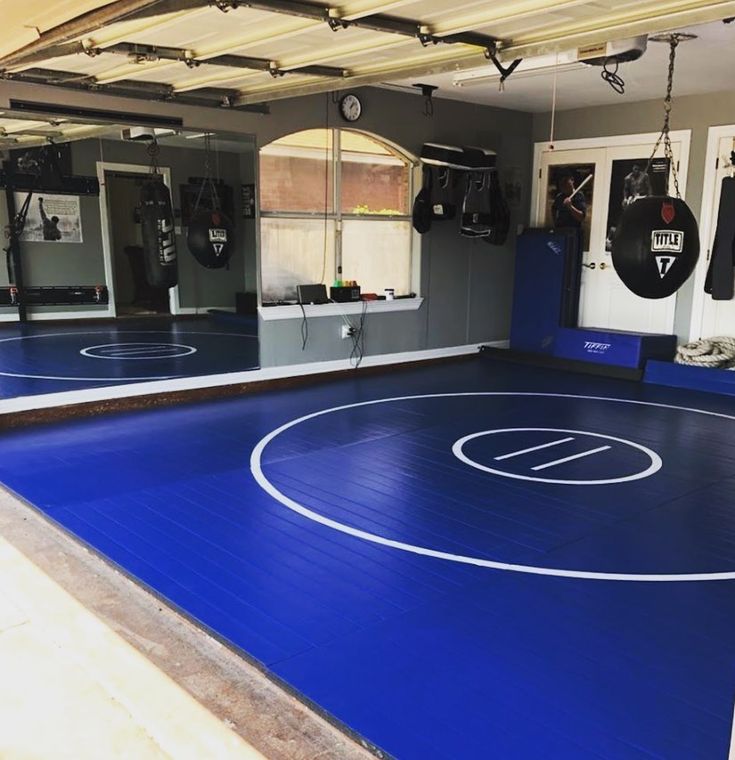 an indoor gym with blue flooring and punching pads