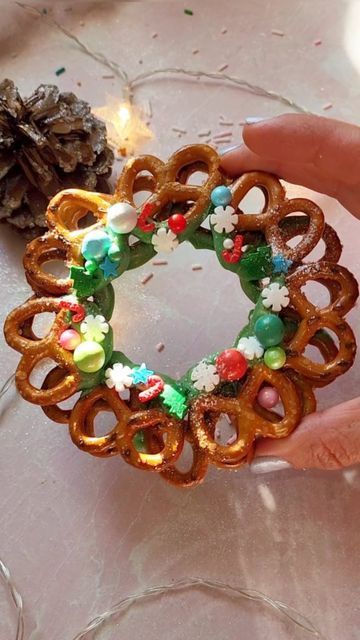 a hand holding a ring made out of pretzels and other items on a table