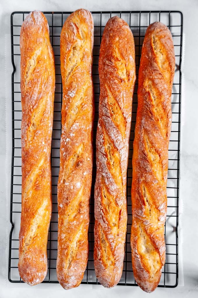 four loaves of bread sitting on top of a cooling rack next to each other