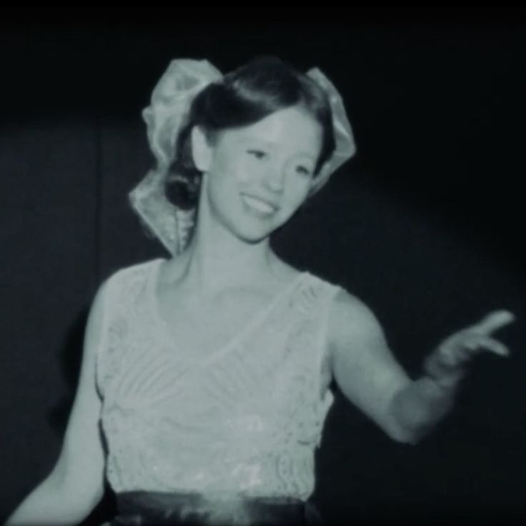 a black and white photo of a woman in a dress pointing to something on her finger