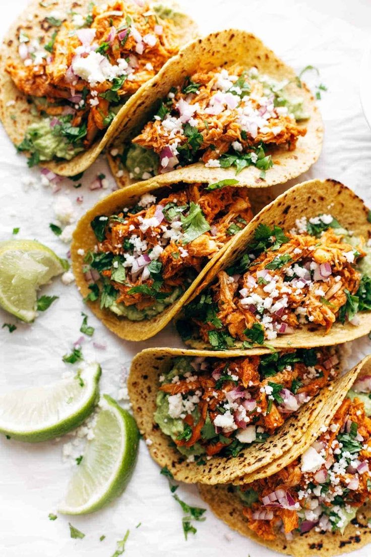 four fish tacos with cilantro, lime and feta cheese on top