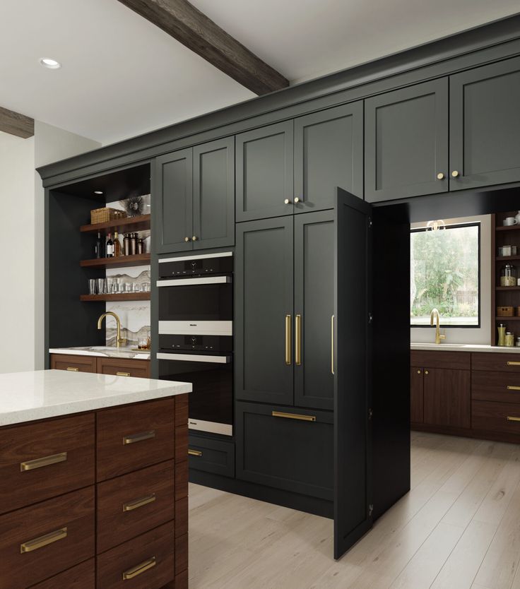 a large kitchen with black cabinets and white counter tops, wood flooring and an island