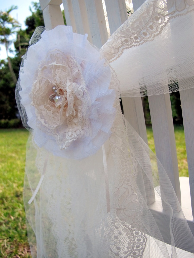 a white chair with a flower on it and lace around the armrests,