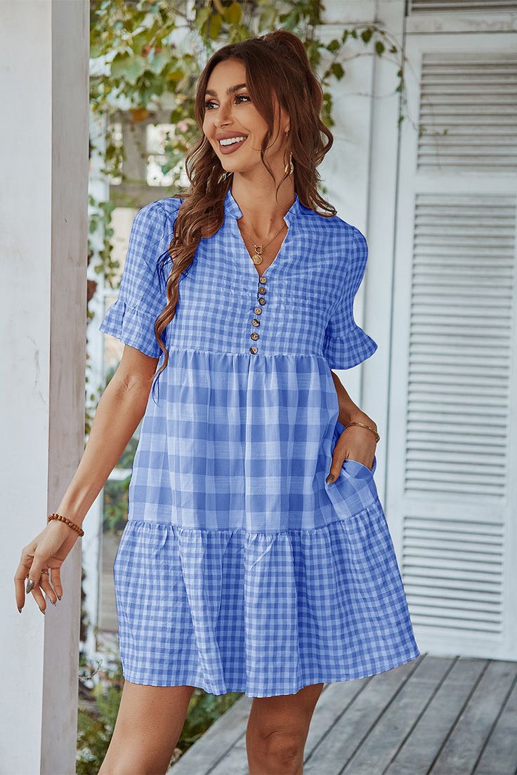 Our Genista Dress comes in a blue & white tone tartan print. It features a v neckline and side pockets short sleeves for a relaxed comfortable fit. This gingham mini pairs beautifully with our heels or sandals for a fun casual look! Size Guide: Chloé is 5’7” tall, and has a 32.88” bust, 25.59” waist, & 36.2” hi Blue Knee-length Mini Dress With Button Closure, Casual Mini Dress With Buttoned Pockets, Blue Mini Dress With Button Closure And Short Sleeves, Light Blue Button-up Beach Dresses, Blue Mini Dress With Buttons And Short Sleeves, Casual V-neck Dresses With Button Cuffs, Blue V-neck Dress With Buttons, Blue Button-up Mini Dress For Vacation, Vacation Mini Dress With Short Sleeves And Button Closure