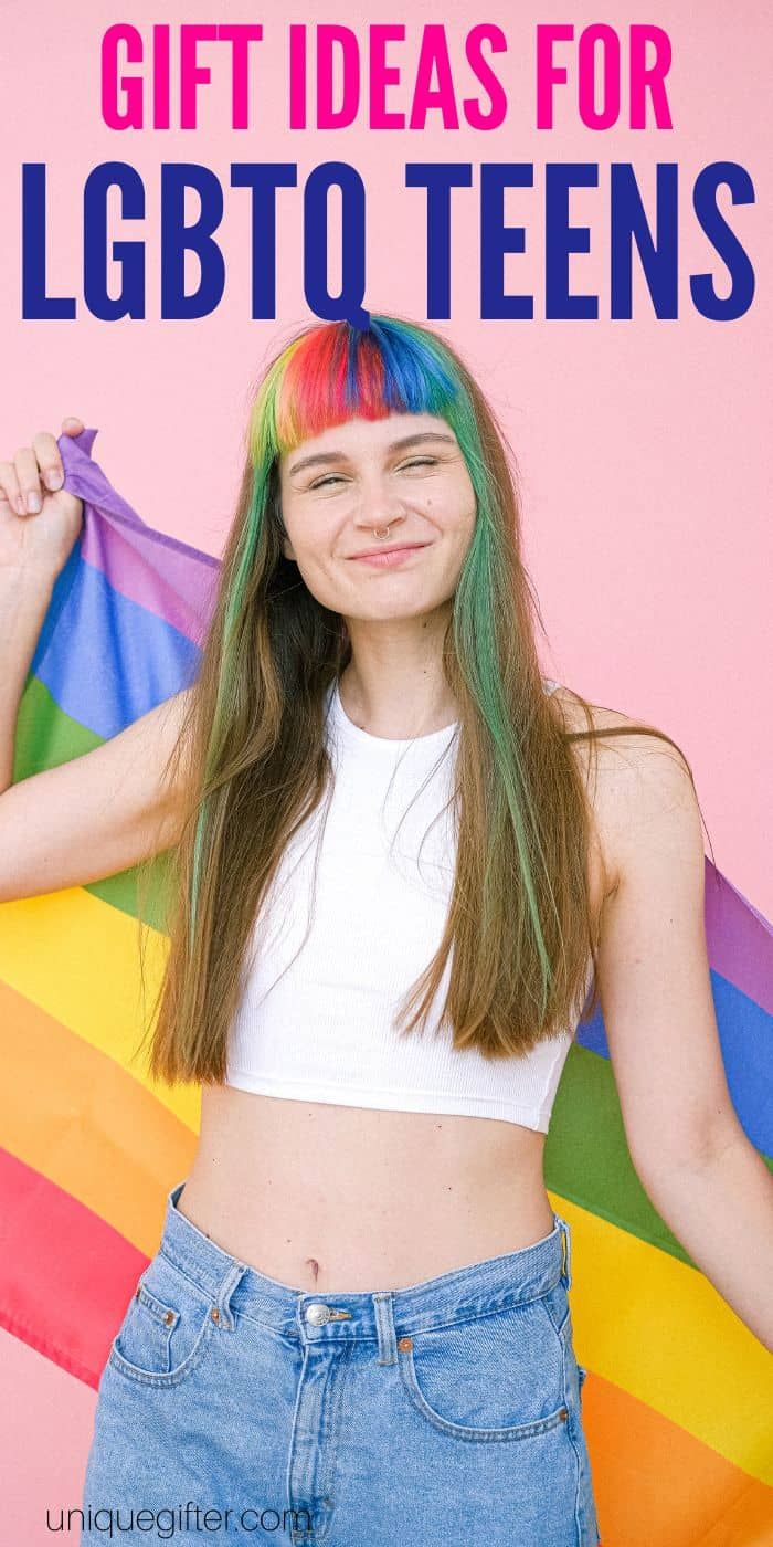 a girl with rainbow hair and blue jeans is holding a colorful flag in front of her face