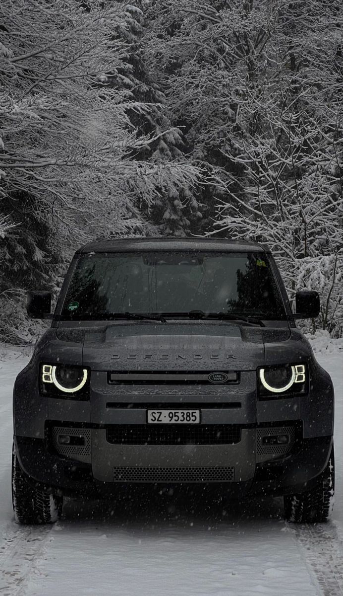 a black truck driving down a snow covered road