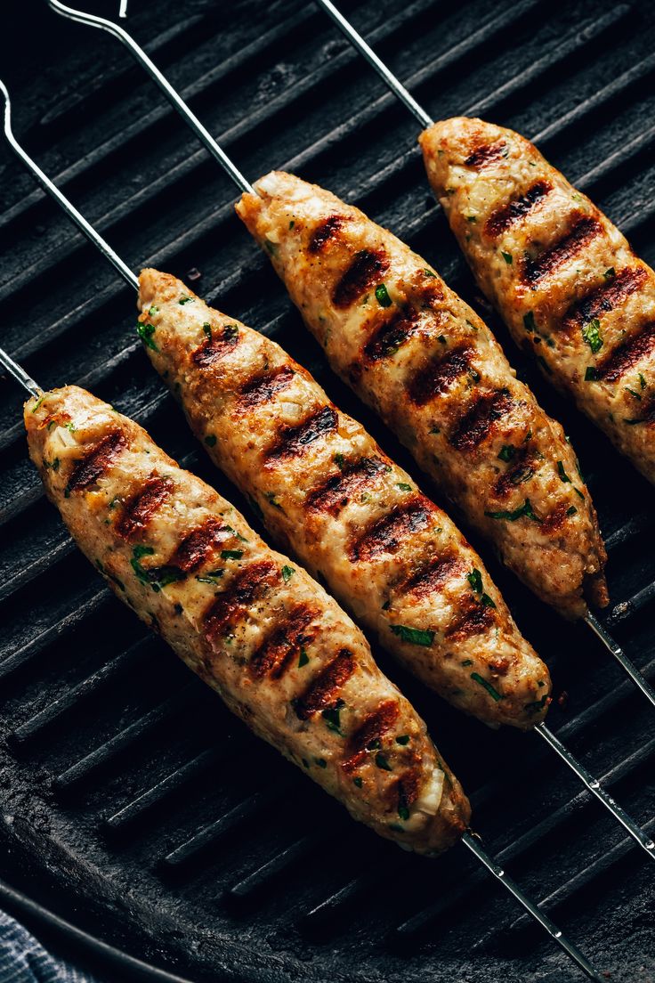 grilled chicken skewers on a grill with tongs