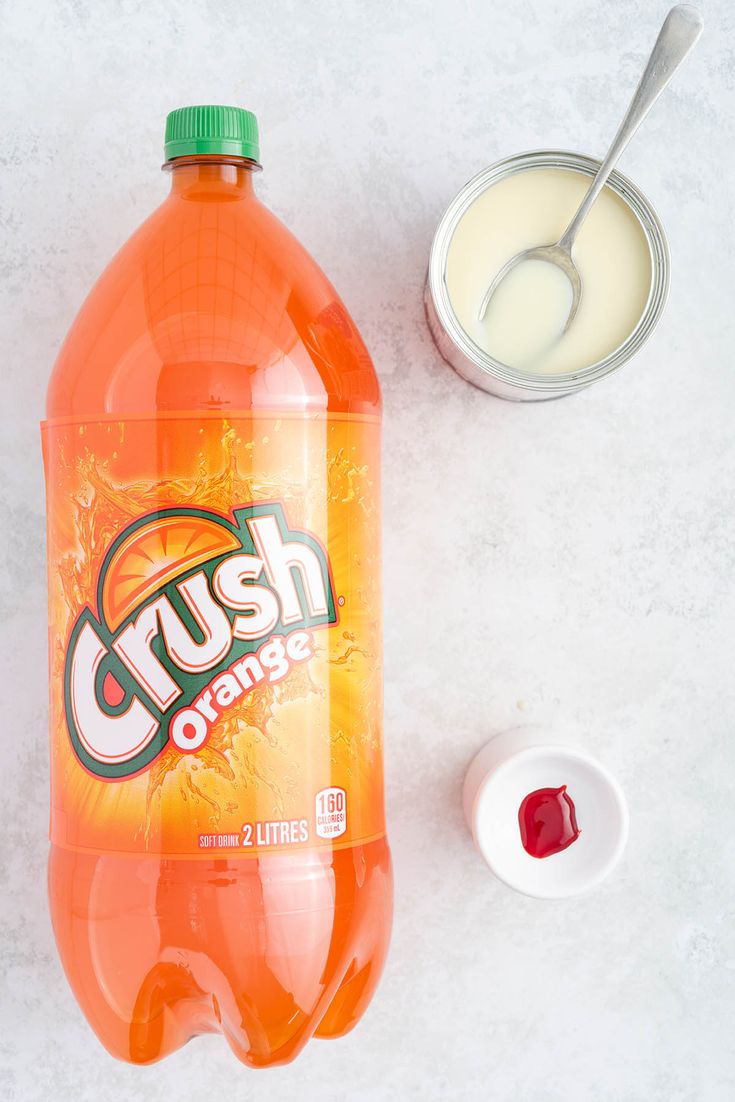 a bottle of crush orange juice next to a bowl of yogurt and a spoon