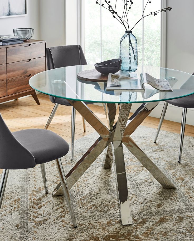 a glass table with chairs around it in front of a window and rug on the floor