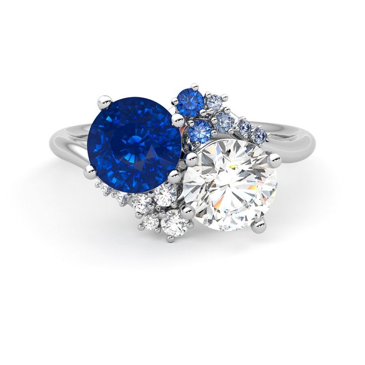 an engagement ring with two blue and white stones on the side, surrounded by diamonds