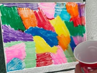 a person holding a cup in front of a colorful painting on a white wall with red trim