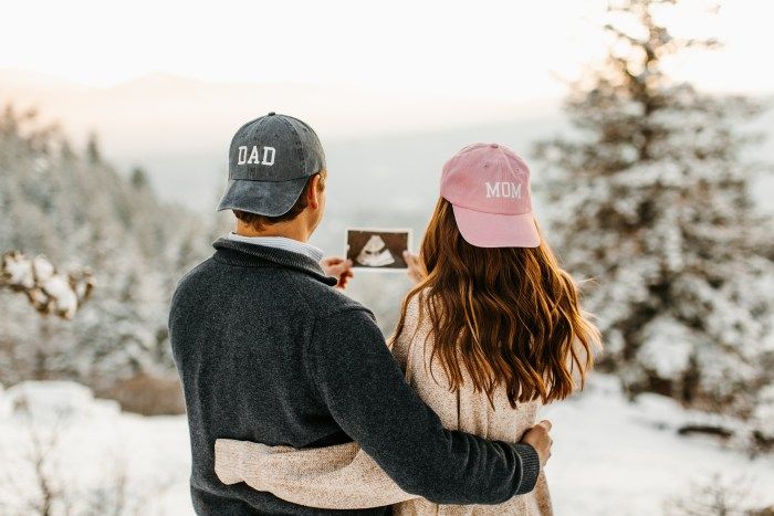 a man and woman standing next to each other in the snow with their arms around each other