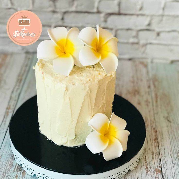 a cake with white frosting and yellow flowers sitting on top of a black plate