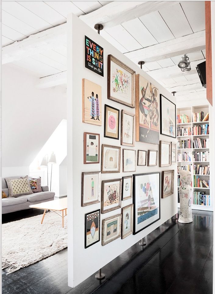 a living room filled with lots of framed pictures on the wall next to a couch