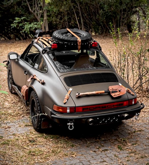 an old car parked on the side of a road with luggage strapped to it's roof