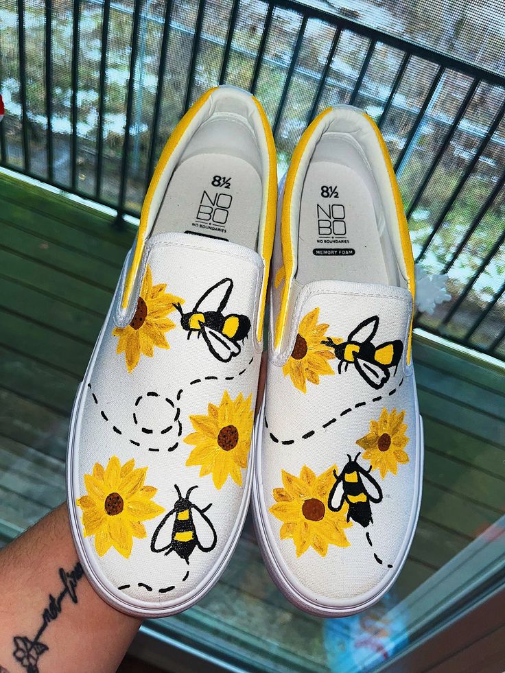 someone has painted sunflowers and bees on their white slip - ons with yellow trim