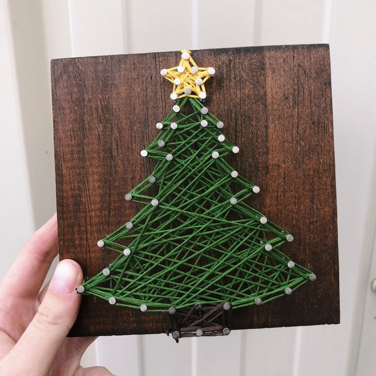 a small christmas tree made out of string on a wooden board with a star hanging from the top