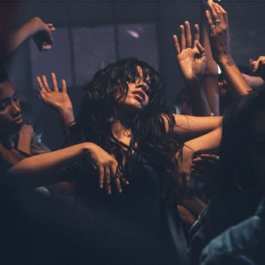 a group of people standing around each other with their hands in the air and one woman holding her arms up