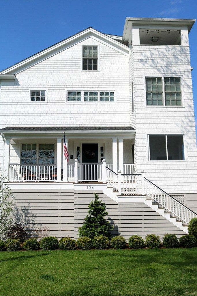 a white house with stairs leading up to the front door and second story on a sunny day