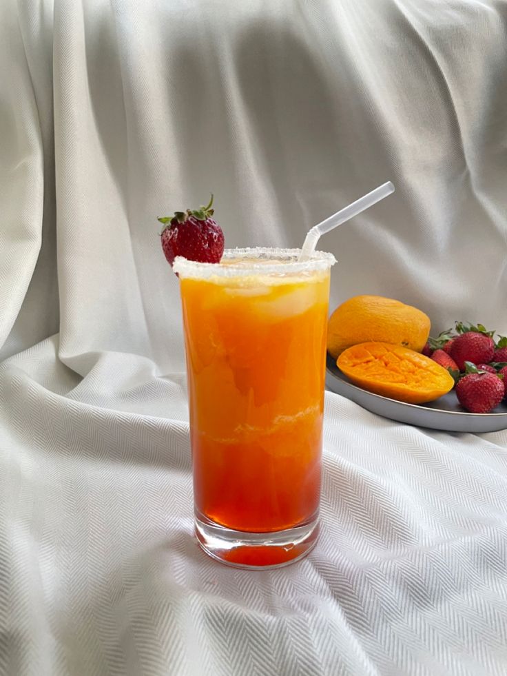 an orange drink with strawberries on the side