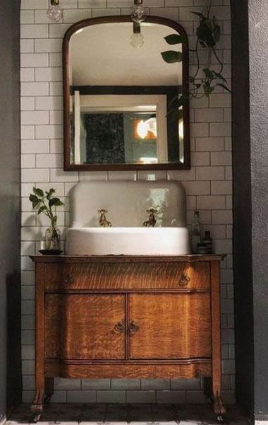 a bathroom sink sitting under a mirror on top of a wooden cabinet next to a white tiled wall