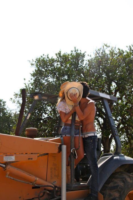 two people standing on the back of a tractor with their arms around each other's shoulders