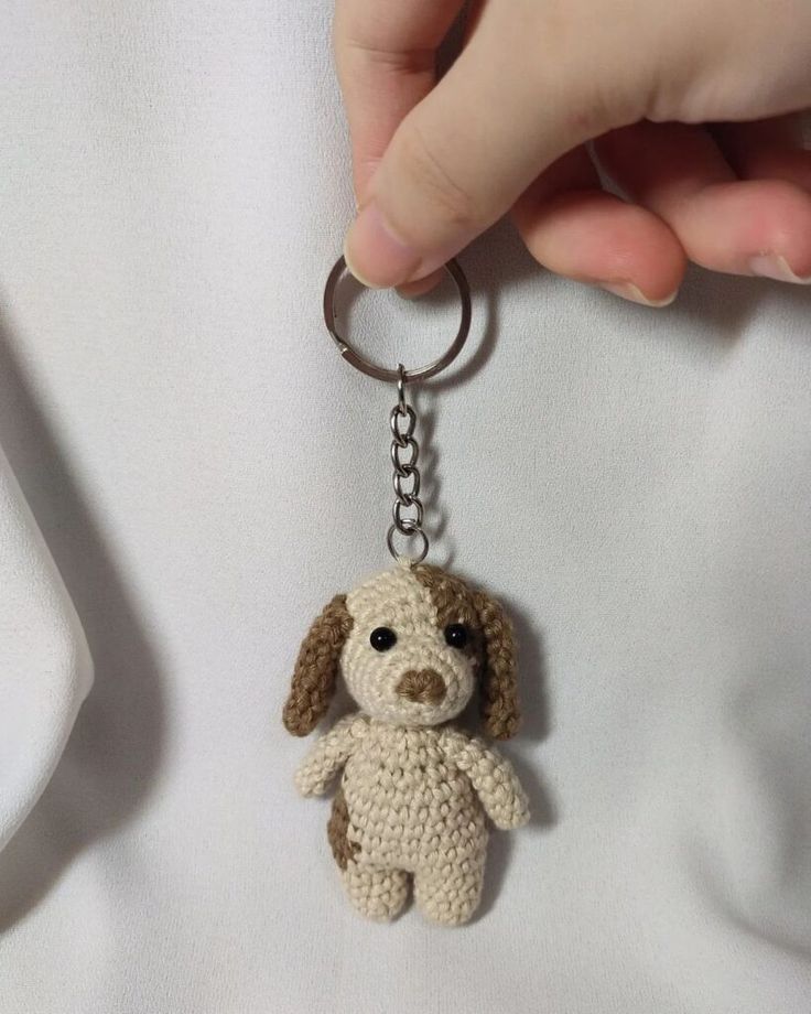 a hand holding a keychain with a small dog on it's side