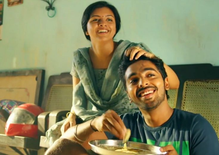 a man sitting next to a woman holding a bowl of food in front of her