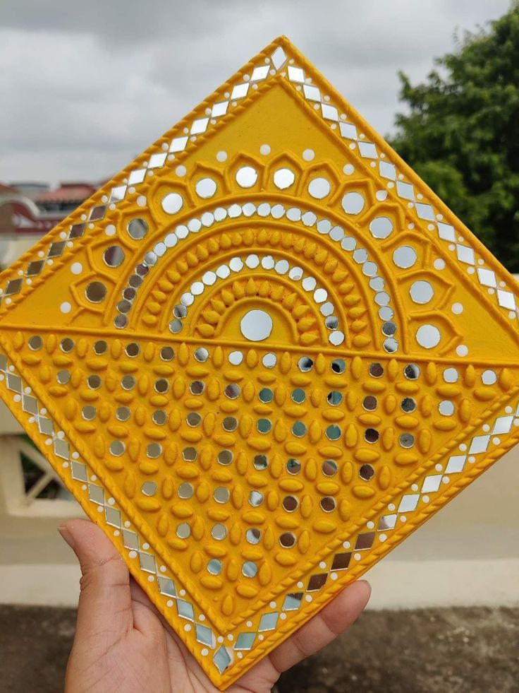 a hand holding up a yellow decorative object