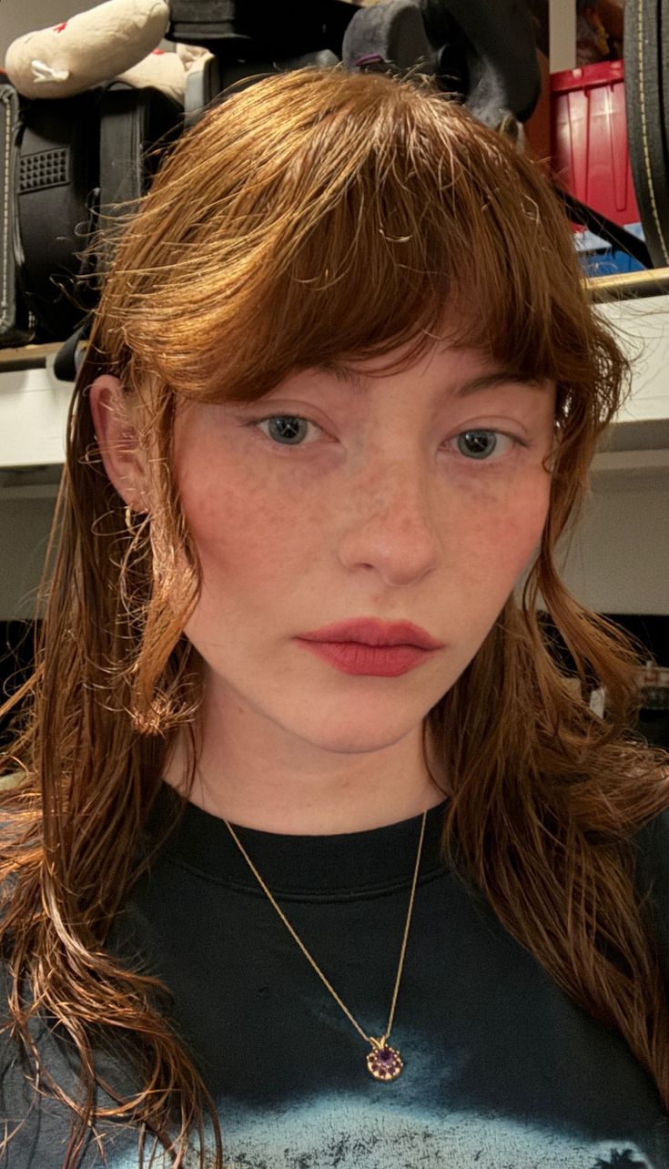 a young woman with freckles and blue eyes is looking at the camera while wearing a black t - shirt