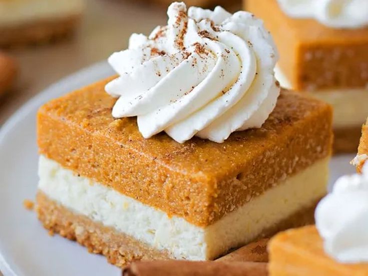 several slices of pumpkin cheesecake with whipped cream on top and cinnamon sticks in the foreground