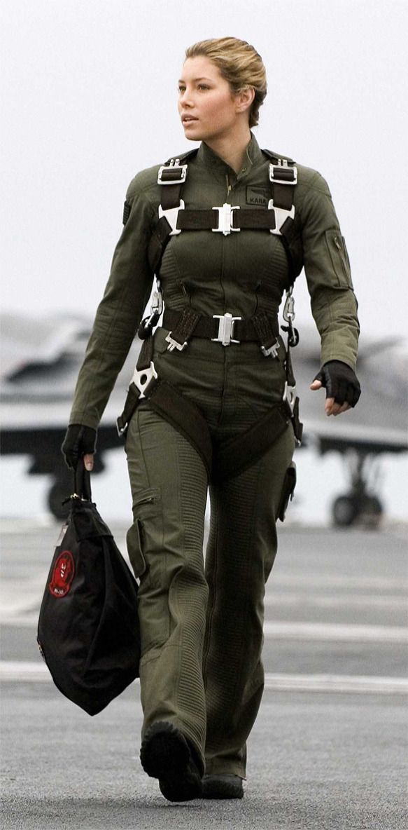 a woman in an air force uniform walking on the tarmac with a handbag