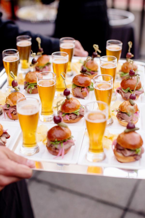 a platter filled with lots of different types of sandwiches and glasses full of beer