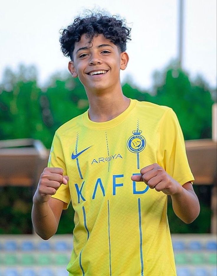 a young boy in a yellow shirt holding a frisbee and smiling at the camera